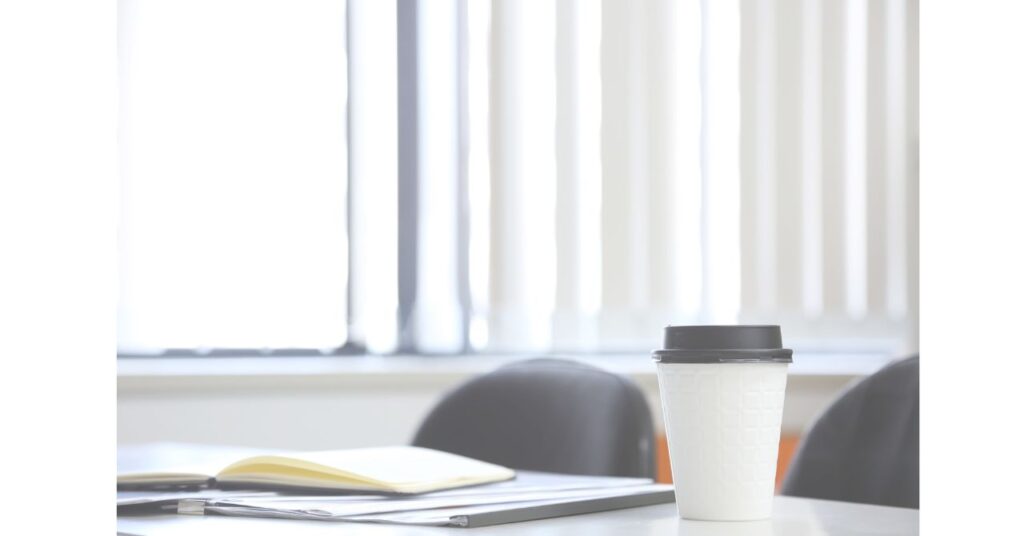 光の中に置かれたコーヒーカップとメモ帳の落ち着いた風景