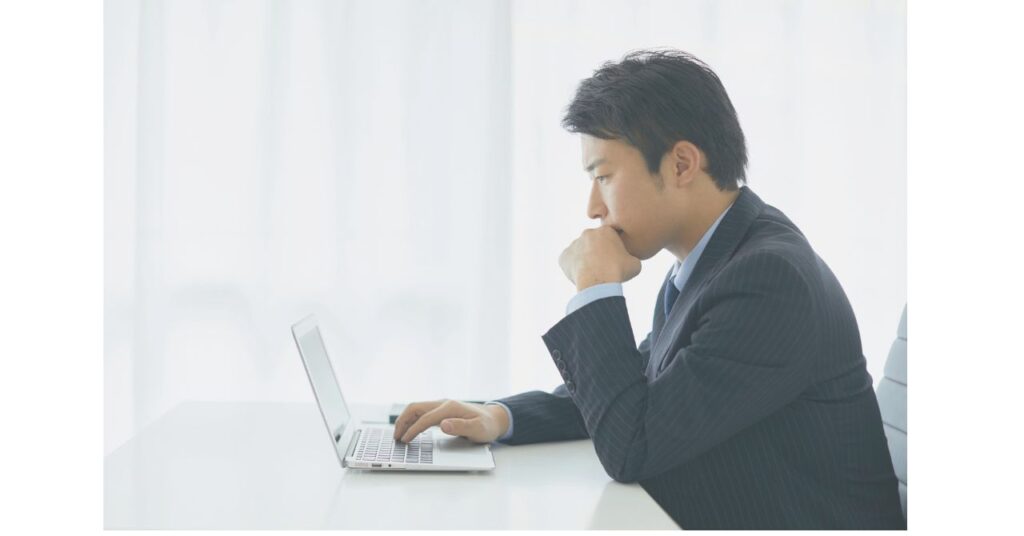 PC前で真剣に資料を見ているビジネスパーソン