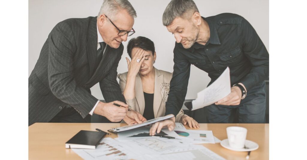 上司と部下に挟まれ、資料を手に困惑する中間管理職の女性