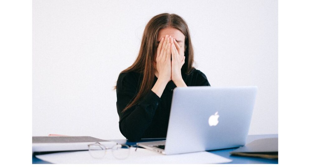 デスクに座り、パソコンの前で肩を落とす40代女性